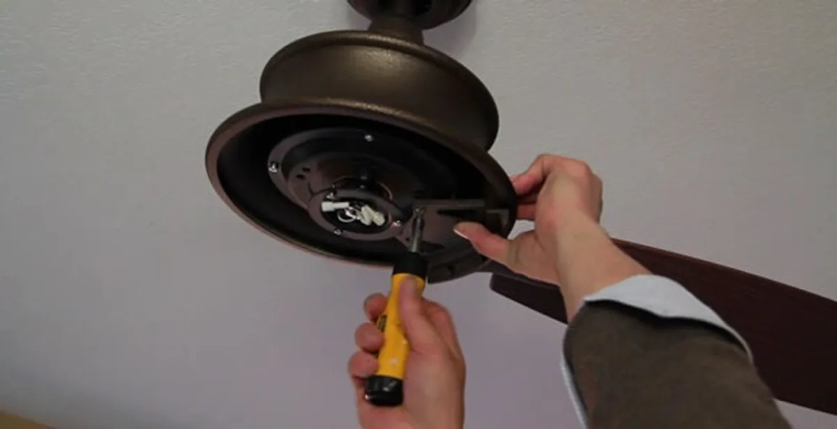 Electrician installing ceiling fan mounting bracket and fixture in Houston, TX