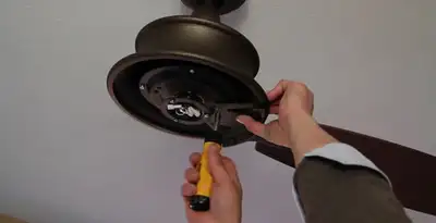 Electrician installing ceiling fan mounting bracket and fixture in Houston, TX
