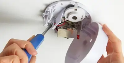 Certified technician wiring smoke detector during installation in Houston, TX